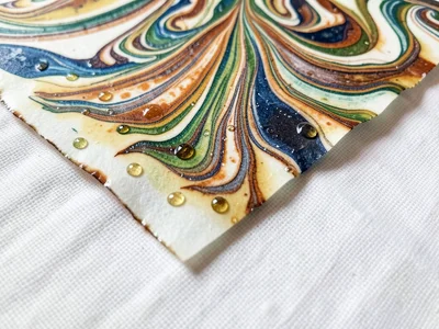 Edge detail of ebru paper showing where marbling meets raw paper border, pigment