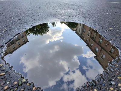 Cloud formation reflected in perfectly still parking lot puddle, sky portal in m