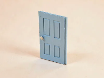 Tiny matte-blue door standing alone on a wide pale-peach floor, scale exaggerate