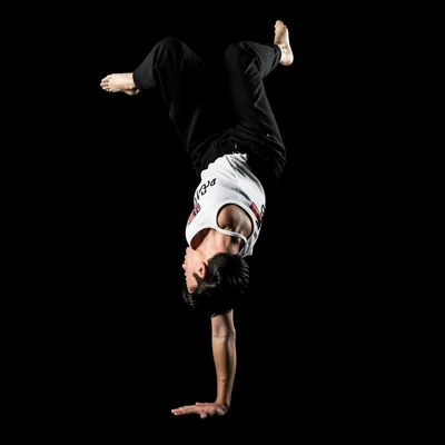 Breakdancer inverted on one hand, impossible angle, gravity defied in pure black