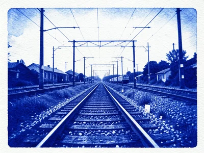 Train tracks converging at a rail yard with overhead electrical lines
