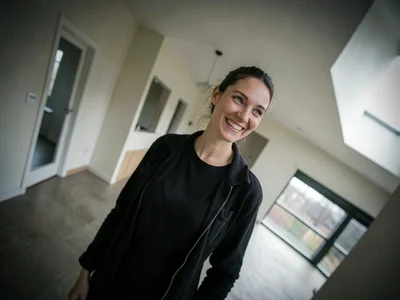 Real estate agent alone in an empty house, her smile at an angle that matches no
