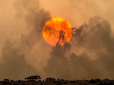 Sun as blood orange disk through thick dust layer