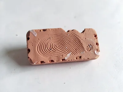 Notched terracotta brick fragment with thumb-pressed mortar lines and fingernail