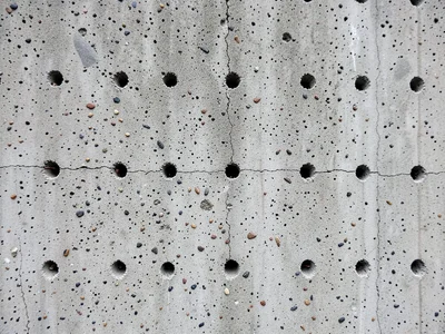 Concrete wall with formwork tie-hole pattern, regular grid of small circular plu