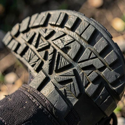 Macro hero of a hiking boot's vibram-style sole, deep tooled lugs casting cool m