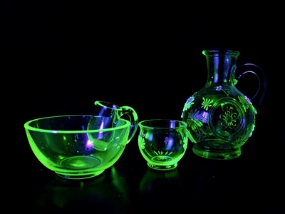 A collection of vintage uranium glass vessels glowing bright green under UV — bo