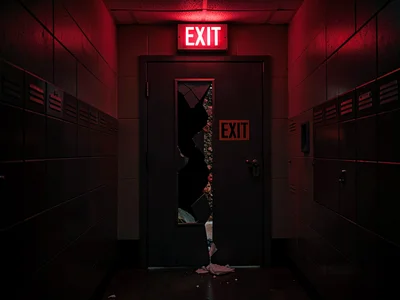 Janitor's closet door cracked, EXIT sign spilling in, the between-jobs solitude