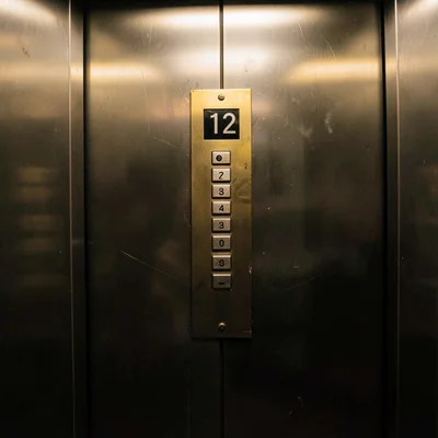 Elevator button panel with floor 12 illuminated in brass housing