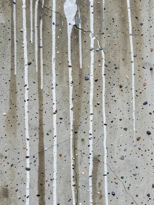 Weathered concrete wall with vertical rain staining streaks, calcium carbonate d