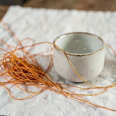 loose handful of saffron threads scattered around a small porcelain ramekin on l