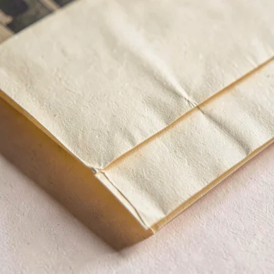 Macro of a folded film inventory sleeve with crease shadows and warm cream paper