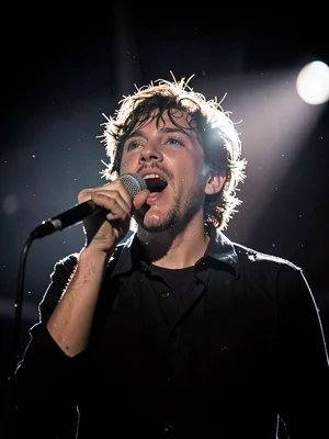 Singer at microphone backlit by single stage light, hair creating halo of light,
