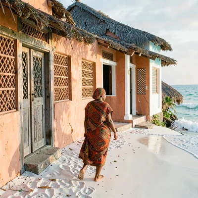 Coastal architecture photograph with Swahili influences, Woman in kanga wrapped 