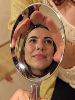 Person's face reflected in spoon, curved and stretched, domestic funhouse mirror