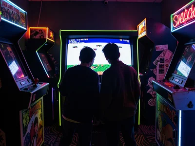 Two Players Silhouetted by Arcade Screen Glow