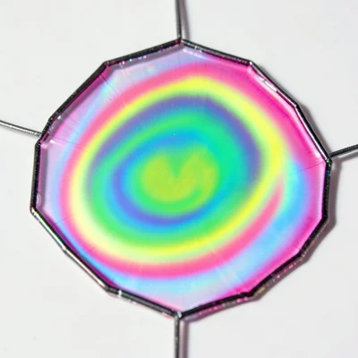 Soap film stretched across hexagonal wire frame, psychedelic color gradient flow
