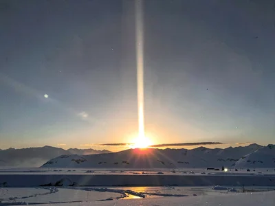 Light pillar extending vertically from setting sun
