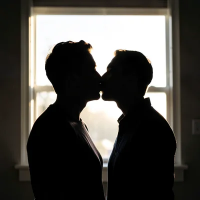Two people kissing silhouetted against a bright window, their edges dissolving i