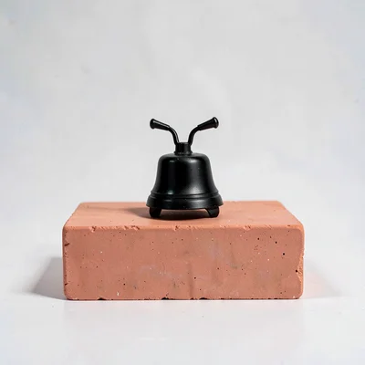 Centered hero of a small bike bell silhouette on a coral block, hairline shadow