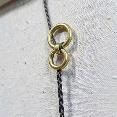 Macro of a hanging hardware on the back of a canvas, brass d-ring and braided wi