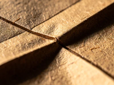 Valley fold crease line, sharp depression in paper surface creating shadow line 