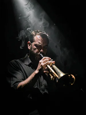 Trumpet player in spotlight, instrument catching hard light, face emerging parti