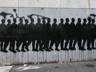 Crowd of faceless silhouette figures marching, repeated stencil across a long gr