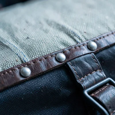 Cross-section study of a luggage edge revealing canvas, leather, riveted reinfor
