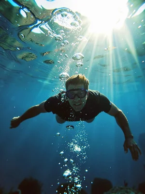 Swimmer underwater, bubbles rising, reversal making them fall through light