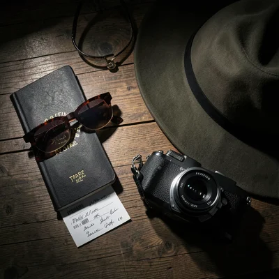 Travel flat lay: passport, sunglasses, camera, plane ticket, hat, on wooden surf