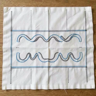 White cotton pre-embroidery — fabric laid flat with chalk-marked guide lines for