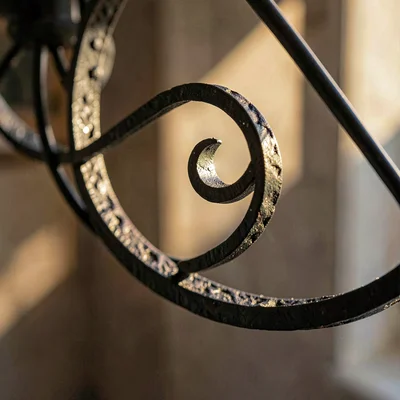 Mineral-cut close on iron chandelier curl with carbon scale, raking light