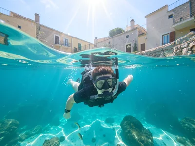 Snorkeler floating face-down, seen from below with sun rays penetrating the surf