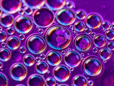 Oil bubble cells on deep purple water, each sphere containing inverted purple wo