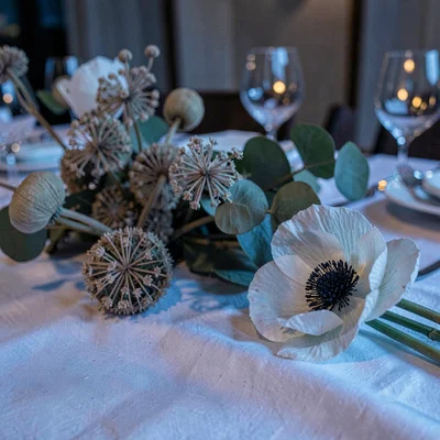Editorial close-up of a winter event tablescape with dried allium, eucalyptus po