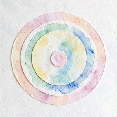 Cut-paper concentric circles in pastel layers radiating from a center paper dot