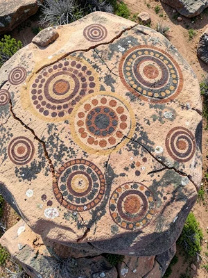 Rock art site — weathered sandstone boulder covered in carved cup-and-ring marks