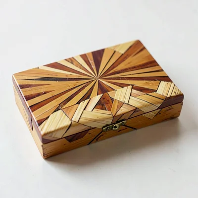 A straw marquetry box lid with a sunburst pattern in warm amber split straws
