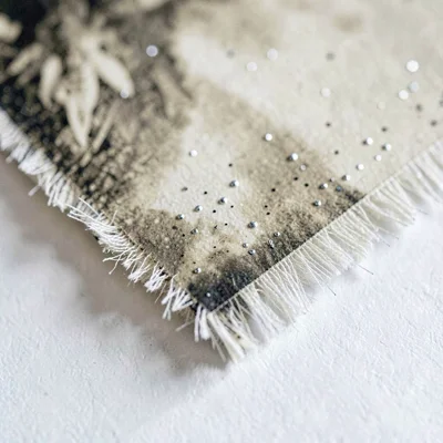 Macro of a foxed sepia print edge with feathered fibers and tiny silver speckles