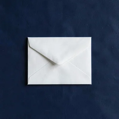 Centered hero of a small white envelope on a deep navy backdrop, even diffuse li