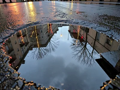 Christmas lights reflected in street puddle after winter rain, inverted glow