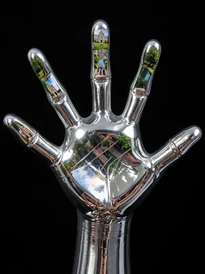 Human hand made of liquid mercury reaching toward camera, each finger reflecting