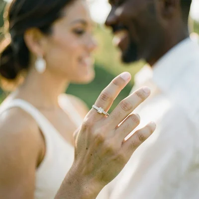 Engagement ring on finger, couple beyond blurred