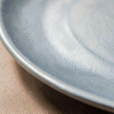 Tight mineral cut of a plate rim showing a soft satin matte finish, hairline gla