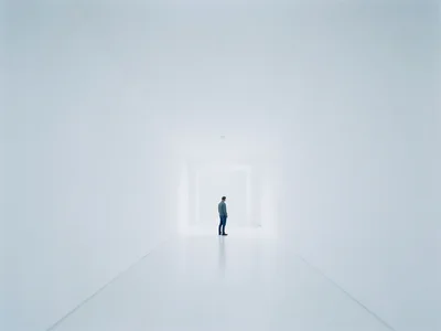 Person standing at the end of an endless white corridor, tiny figure, vast empti
