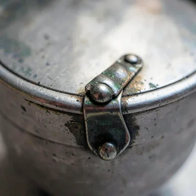 Mineral-cut close on a pewter stein lid hinge with patina, raking light
