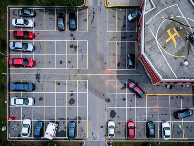 A hospital parking lot at shift change from above, the 7am to 7pm nursing shift 