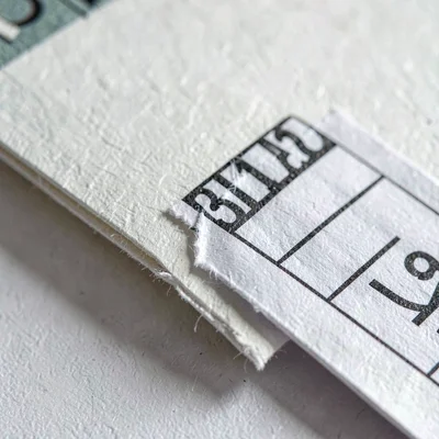 Paper close-up of a price sticker peeled half off a sleeve corner