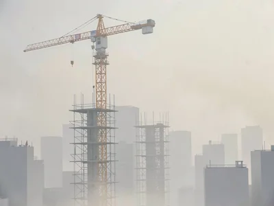 Construction crane standing motionless above scaffolded shells, surrounding city